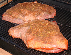 Rubbed beef brisket smoking on the grill