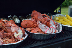 Lobster, corn, and baked potatoes ready to serve.